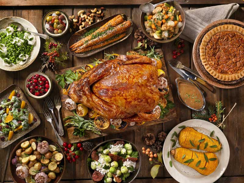 Holiday dinner table with a roast turkey, pecan pie and side dishes