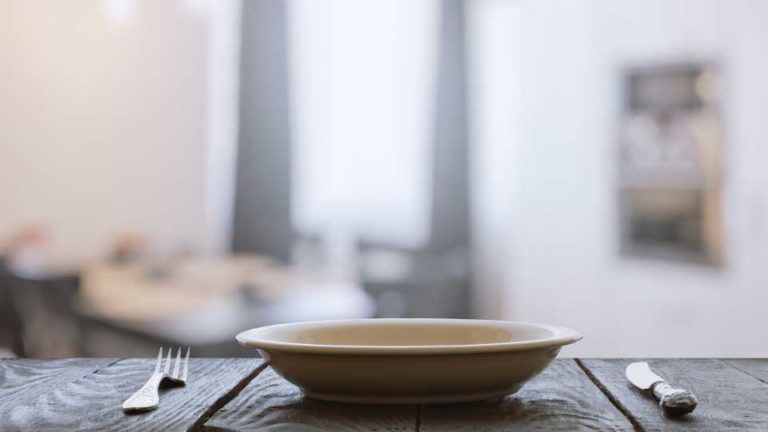 empty plate with fork and knife on wooden table