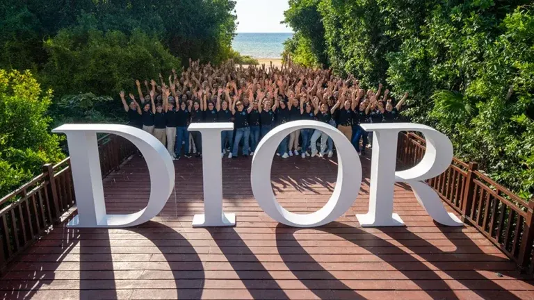 Dior sales team group photo at Riviera Maya off-site meeting with large branded signage