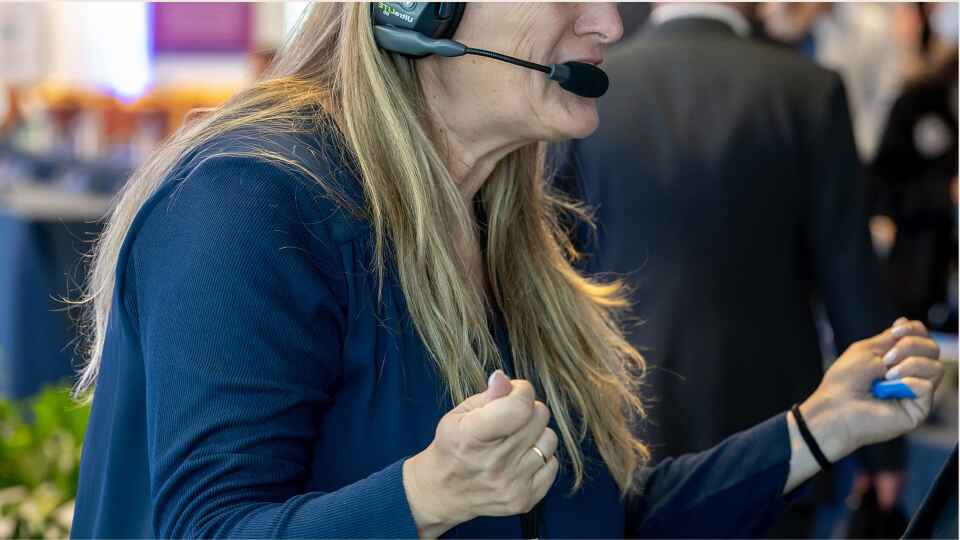Valerie Bihet wearing a headset directing show flow on site, the kind of live control a corporate event agency provides.